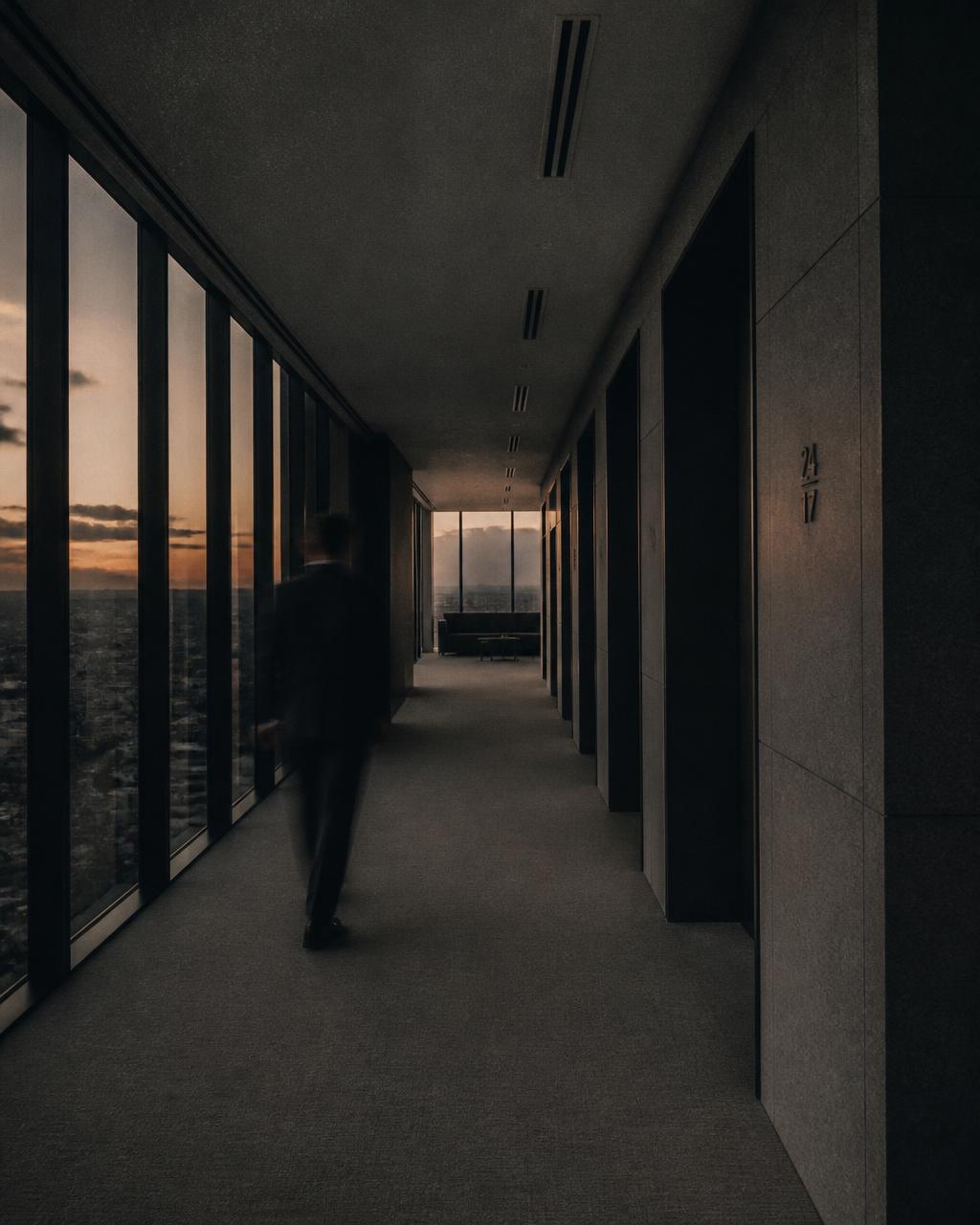 Corredor corporativo ao entardecer com uma silhueta em movimento